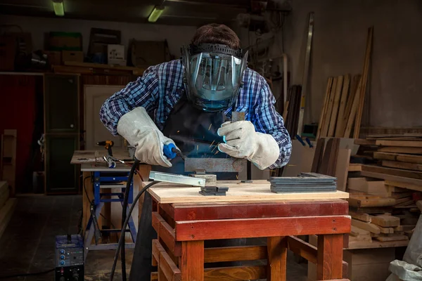 Maske ve kaynakçılar deri, kaynak bir genç adam kaynakçı üniformalı, Kaynak metali ile atölye, mavi ve turuncu kıvılcım sinek iki yanda makinesinde ark