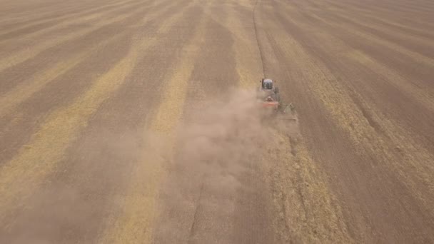 Vue aérienne d'un tracteur agricole plantant des céréales sur des champs cultivés. Tournage à partir d'un tracteur quadrocopter sur le champ de récolte  