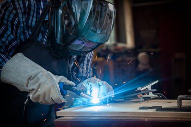 Güçlü adam Kaynakçı çalışmalarında çalışkan elbise ve bir kaynak makine metal kaynak