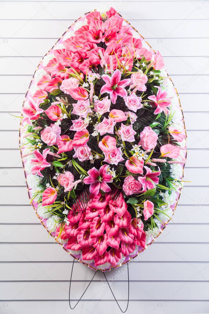 Luxury funeral wreath with pink and purple flowers on a white striped isolated background