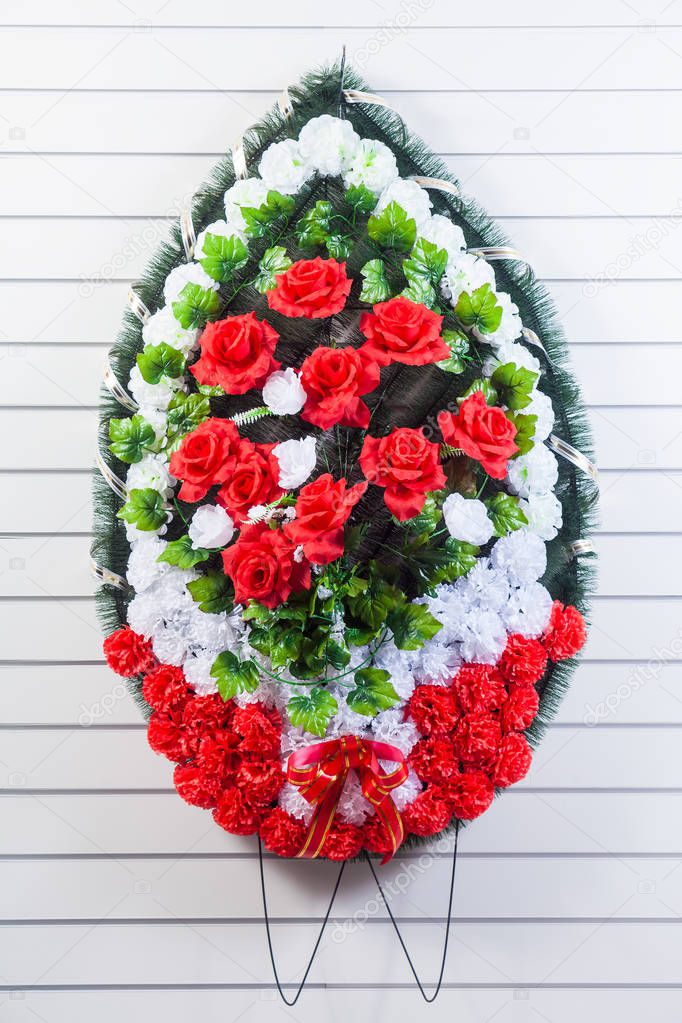 Luxury funeral wreath with red and white flowers on a white striped isolated background