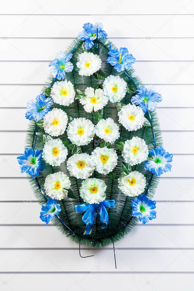 Luxury funeral wreath with blue and white flowers on a white striped isolated background