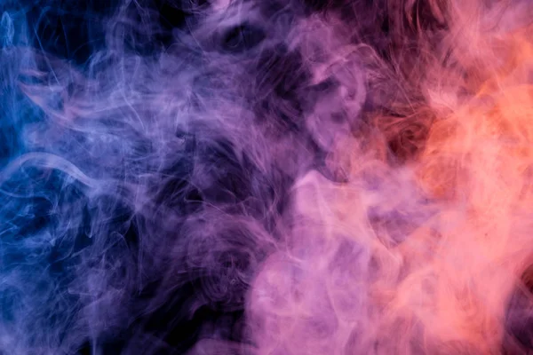 Cloud of pink, red and blue  smoke on a black isolated background. Background from the smoke of vap