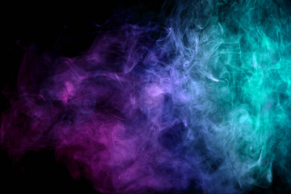 Colorful pink, blue and green smoke on a black isolated background. Background from the smoke of vap