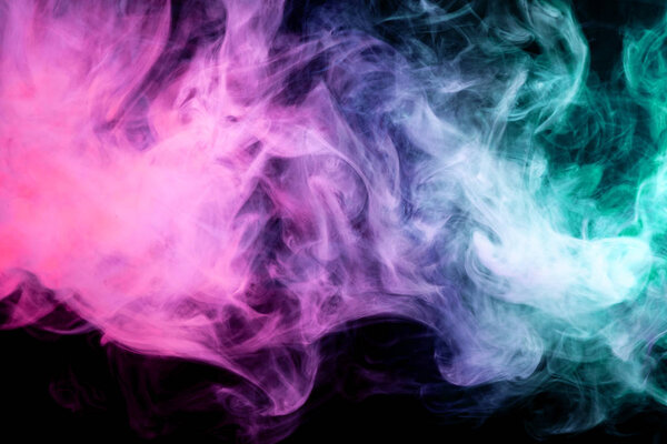 Thick colorful smoke of pink, blue and green on a black isolated background. Background from the smoke of vap