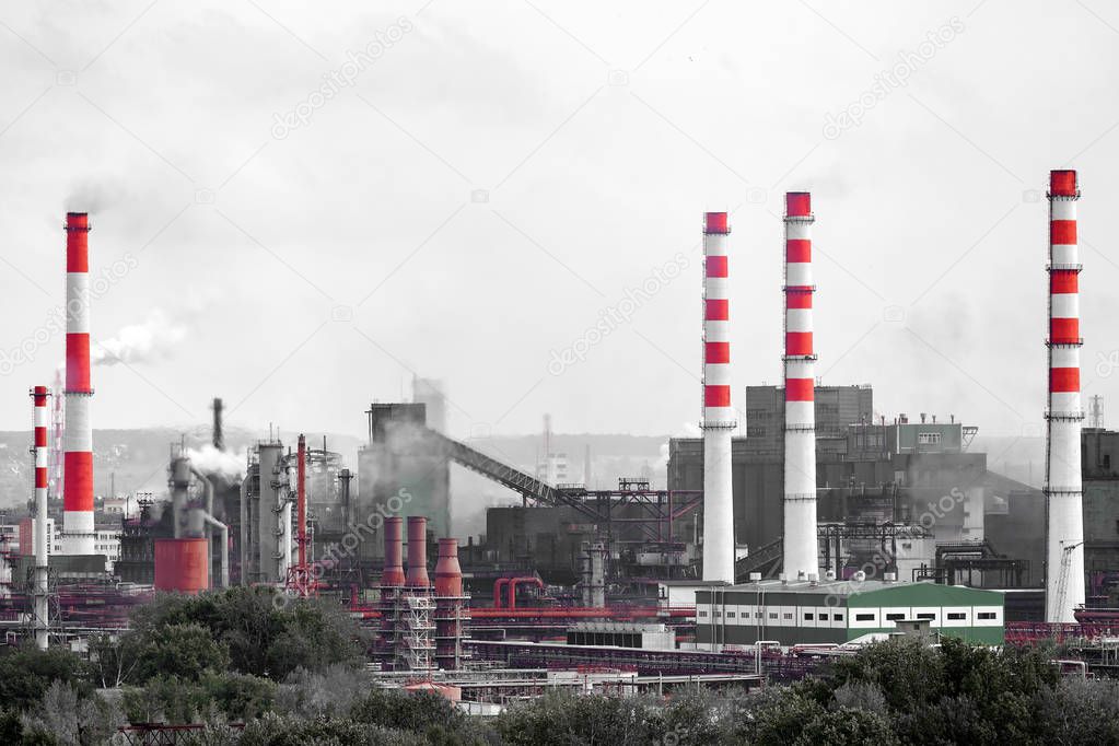 The landscape of a huge industrial city with factories and high cranes from which come out with huge smoke puffs. Pollution of the environment by plants and industries
