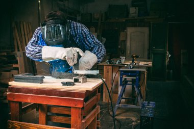 Maske ve kaynakçılar deri, kaynak bir genç adam kaynakçı üniformalı, Kaynak metali ile atölye, mavi ve turuncu kıvılcım sinek iki yanda makinesinde ark