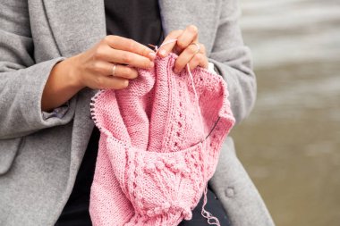 Bir genç pembe şapkalı örgü iğneleri karşı deniz güneşli bir sonbahar günde örgü trendy ceket giymiş kadın evli og kapatın. Serbest yaratıcı çalışma ve yaşam kavramı