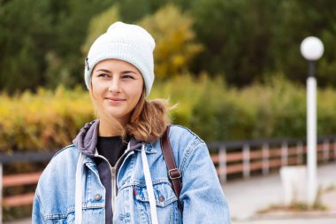 Mavi örgü şapka ve denim ceket giyen muhteşem darkhaired kadın deniz feneri arka plan üzerinde poz
