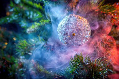 Parlak dekorasyon Noel topları bir Noel ağacı arka plan üzerinde renkli mor-kırmızı duman gümüş. Modern bir Noel kartı kavramı. 