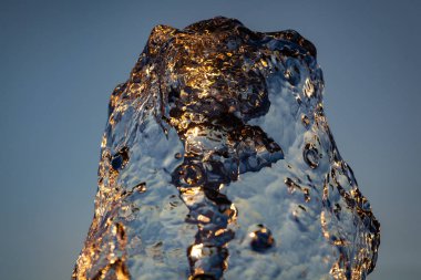 Güneş ışınlarının altında mavi bir zemin üzerinde bir sürü damla ve kabarcık olan su püskürtüleri. Büyük bir plan Büyük bir çeşmenin su dalgalarının dokusu