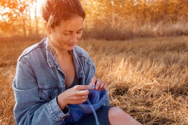 Açık havada bir freelancer iş kavramı. Genç bir kadın bir kot ceket ve ekose arka plan sonbahar sahada iğne ile şapka örgü elbise.