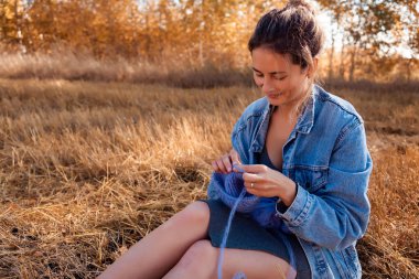 Açık havada bir freelancer iş kavramı. Genç bir kadın bir kot ceket ve ekose arka plan sonbahar sahada iğne ile şapka örgü elbise.