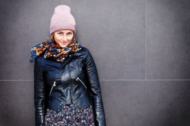 Esmer saçlı şapka, deri ceket ve eğleniyor, elbise örgü içinde neşeli genç kadın portre gülümse ve sokak büyük şehir üzerinde iyi günler. şık hipster kadın 