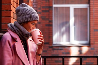 Gitmek için genç çekici Bayan mavi örgü şapka ve pembe ceket kahve iç. Gülümseyen güzel hipster mutlu kadın şık kıyafetlerle sokak, şehirde. Sonbahar eğilim, kentsel stydent tarzı.