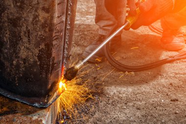 İşçi kesme metal gaz ile kapatın. Bir genç adam kaynakçı kahverengi üniforma, kaynakçılar deri, değirmeni metal bir gaz inşaat sahasında yakın çekim