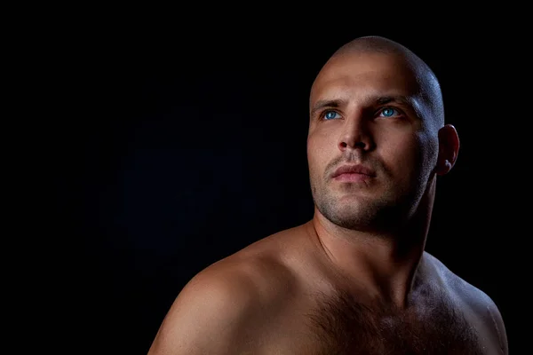 Serious  young bald man standing isolated on a black background and looking away.Portrait Handsome man with confident face in studio