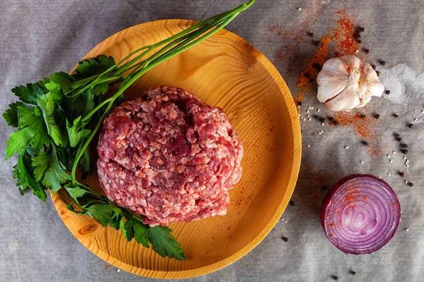 Flat lay. A set of fresh ingredients  for cooking ground beef:beef meat, onion, garlic, tomato, spices, salt, pepper, greenery. The process of cooking meatballs, hamburger, lasagna and other meat dishes