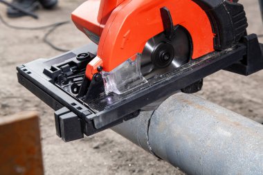 Bir el modern kırmızı daire testere ile inşaat sahasında metal testere bir adam Oluşturucusu'nun yakın çekim. Ağır sanayi işçisi açı değirmeni atölye ile çelik boru kesme. 