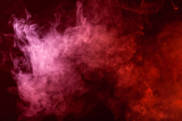 Textural background for creativity. Cloud of red and pink smoke on a black isolated background. Background from the smoke of vap