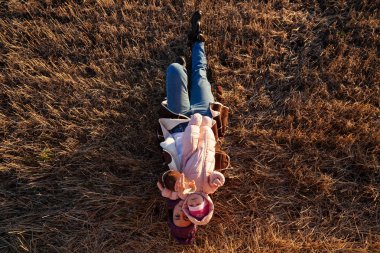 Örgü şapka ve sıcak giysiler ile küçük bebek oyun, güzel bir genç model portresi gün, arka plan haystacks güneşli sonbahar gün tadını çıkarın. Sonbahar sıcak fotoğraf. Kadın gülümsüyor ve göz uzak, neşeli neşeli ruh.