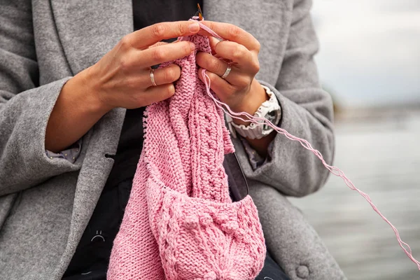 Close-up of a woman knitting with knitting needles from a natural woolen thread a pink sweater, a woman shows how to knit correctly