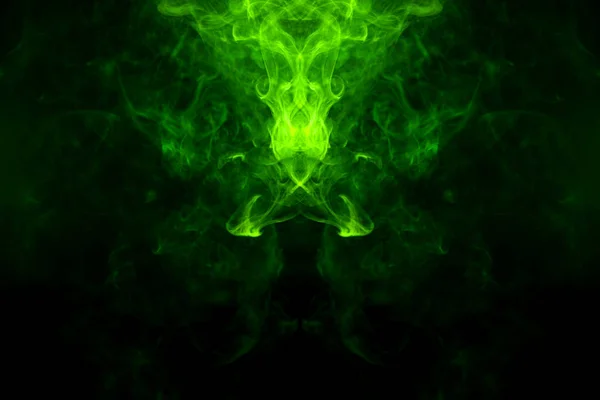 Fantasy print for clothes: t-shirts, sweatshirts.  Colorful green and yellow  smoke in the form of a skull, monster, dragon on a black isolated background. Background from the smoke of vap