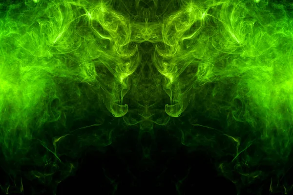 Fantasy print for clothes: t-shirts, sweatshirts.  Colorful green and yellow  smoke in the form of a skull, monster, dragon on a black isolated background. Background from the smoke of vap