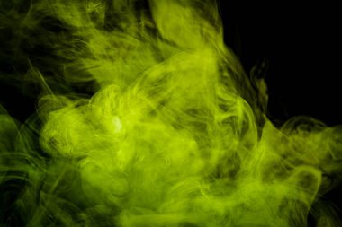 Siyah bir yalıtılmış zemin üzerine yeşil ve sarı renklerin yoğun çok renkli duman. Duman vap arka plan