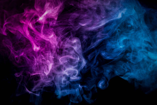 Thick colorful smoke of pink, blue on a black isolated background. Background from the smoke of vap