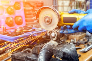 Bir close-up bir oto tamircisi için arka plan araçları farklı yönlerde uçan parlak yanıp söner bir oto tamircisi mengeneye içinde bir araba sessiz blok kesmek için bir metal taşlama kullanarak bir araba tamircisi. Otomatik mekanik çalışmalarını.