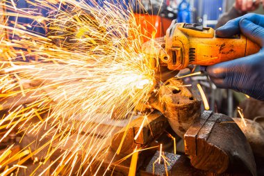 Bir adam metal ahşap bir masa üzerinde bir El Daire testere ile parlak yanıp söner bir oto tamircisi için arka plan araçları farklı yönlerde uçan testere Close-up. Otomatik mekanik çalışmalarını.