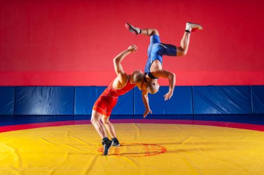 Mavi ve Kırmızı tayt güreş iki güçlü güreşçiler wrestlng ve bir sarı halı spor salonunda güreş güreş suplex yapım vardır. Kıskaç yapan genç erkek.