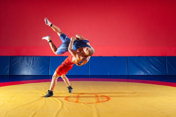 公正なレスリングのコンセプトです 青と赤のタイツをレスリングで つの若い男性は Wrestlng とジムでカーペットをレスリング黄色の腰投げを作る — ストック写真