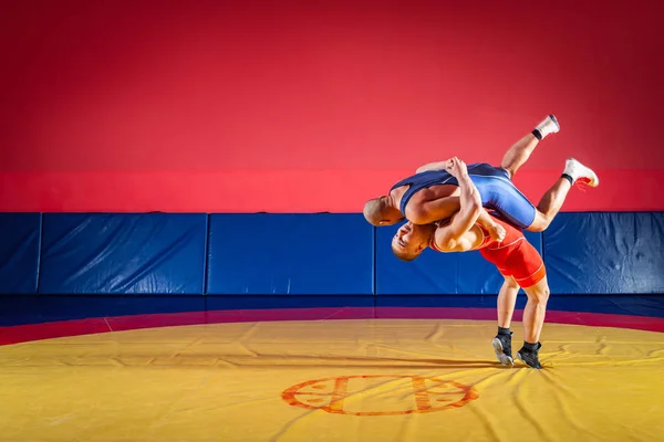 青と赤のタイツをレスリングで つの若い男性は Wrestlng と黄色のカーペットをジムでプロレスのレスリング スープレックスを作るします 公正なレスリングの概念 — ストック写真