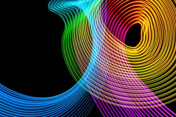 Abstract rainbow neon glowing crossing lines pattern.  Dark background of colorful neon glowing light shapes