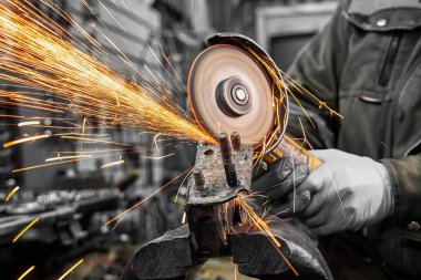Bir genç adam kaynakçı bir mavi eldiven değirmeni bir açı değirmeni atölyede metal, sinek tarafa kıvılcım