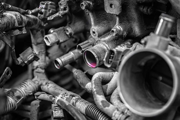 Close-up of engine failure: pink antifreeze flows from the engine pipes of an old car