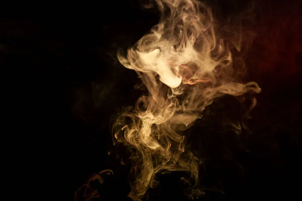 Colorful yellow and orange smoke  on a black isolated background. Background from the smoke of vap