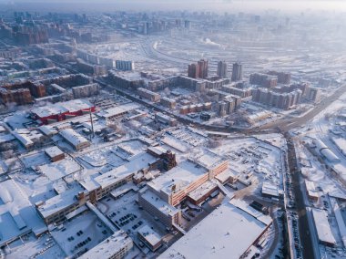 Aerial photography of a modern city: high-rise buildings, a big road, shops and parks on a cold  winter day with a blue sky.Helicopter drone shot
