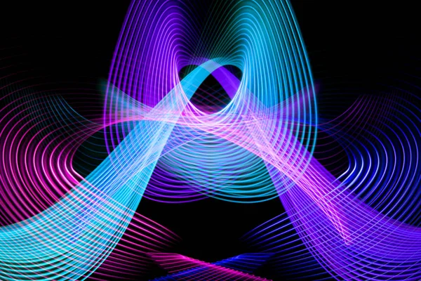 Abstract rainbow neon glowing crossing lines pattern.Dark background of colorful neon yellow, pink and purple glowing light shapes.