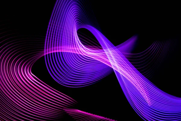 Abstract rainbow neon glowing crossing lines pattern.Dark background of colorful neon yellow, pink and purple glowing light shapes.