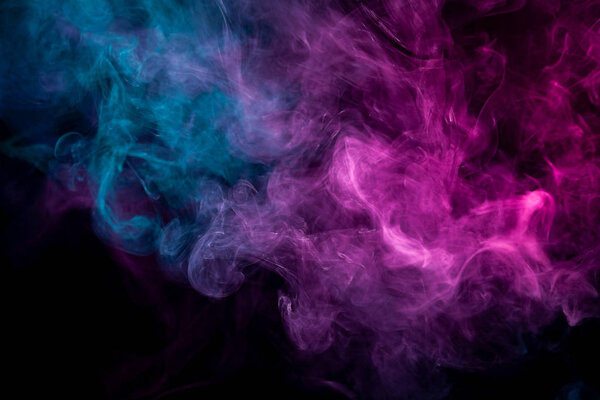 Close up swirling pink and blue smoke on black background