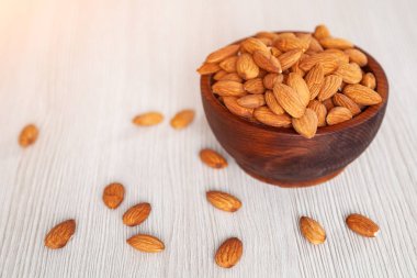 Soyulmuş badem bir sedir çam plaka ahşap izole arka plan üzerinde. Satır badem fındık ile kase. Soyulmuş badem desen