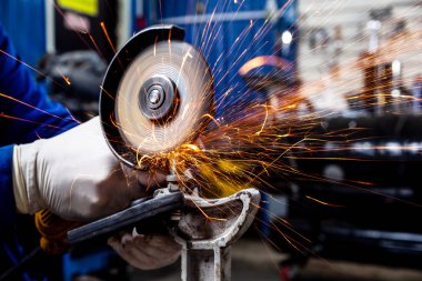 Yakın çekim parlak taraf anında açı kıyma makinesinden kıvılcım. Genç bir erkek kaynakçı bir beyaz eldiven çalışma açısı değirmeni garajda ile metal ürün biler