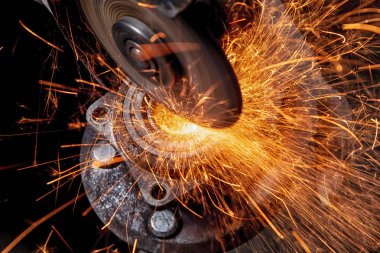 Fabrika, çok sarı ve mavi kıvılcım sinek ayrı bir metal masa üstünde a açı değirmeni makine ile bir metal araba parçası kesme yakın çekim