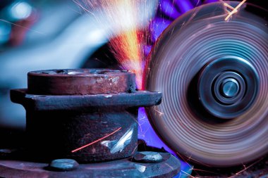 Bir genç adam kaynakçı taşlama atölye bir açı değirmeni metal, sinek tarafa kıvılcım