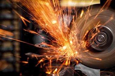 Bir genç adam kaynakçı taşlama atölye bir açı değirmeni metal, sinek tarafa kıvılcım