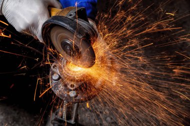 Bir close-up bir oto tamircisi için arka plan araçları farklı yönlerde uçan parlak yanıp söner bir oto tamircisi mengeneye içinde bir araba sessiz blok kesmek için bir metal taşlama kullanarak bir araba tamircisi. Otomatik mekanik çalışmalarını.