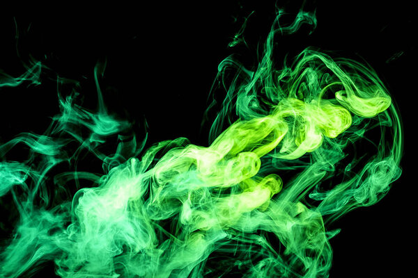 Abstract art colored green smoke on black isolated background. Stop the movement of multicolored smoke on dark backgroun